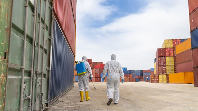 People wearing protective suits spray disinfectant chemicals on the cargo container to prevent the spreading of the coronavirus.
