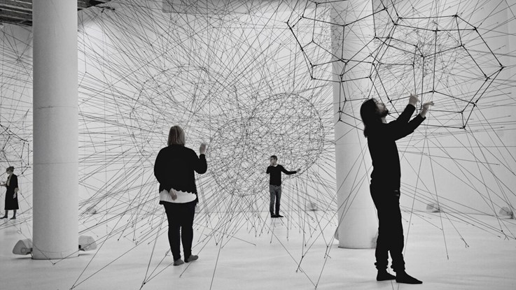 Fyra människor i ett museum som tittar på abstrakt konst