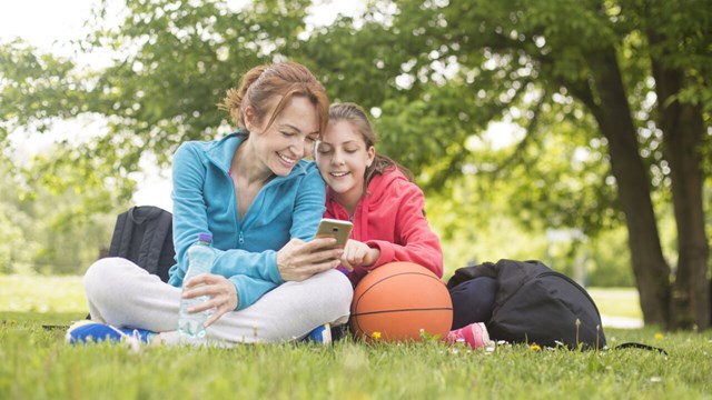 Mother and daughter relaxing in a park. Mature woman about 40 years old and a female child about 11 years old, both Caucasian females.