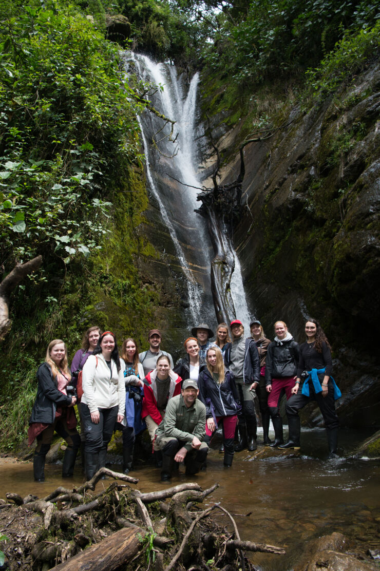 A group of people in front of a waterfall in the rainforest