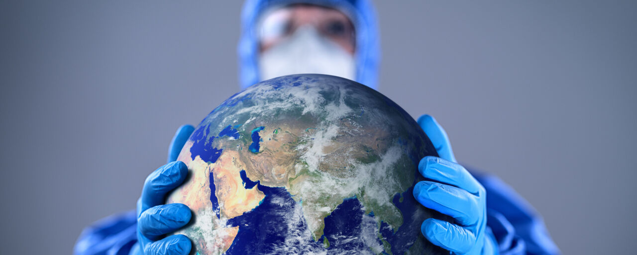 Doctor wearing highly protective suit and holding globe in her hands