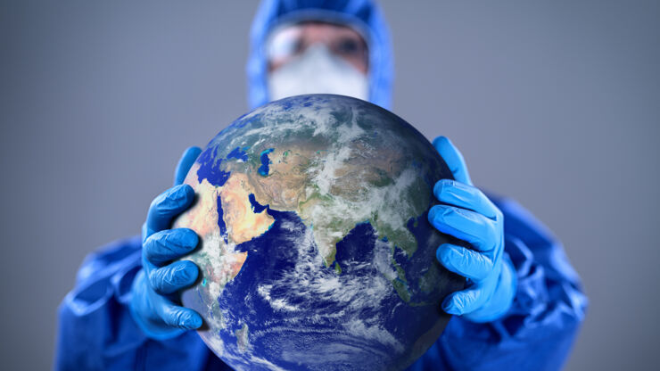 Doctor wearing highly protective suit and holding globe in her hands