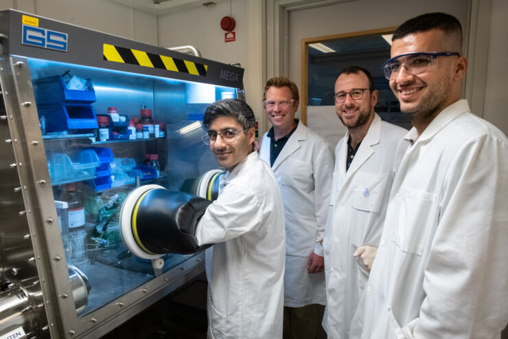 Four researchers in white coats in a chemistry laboratory. 