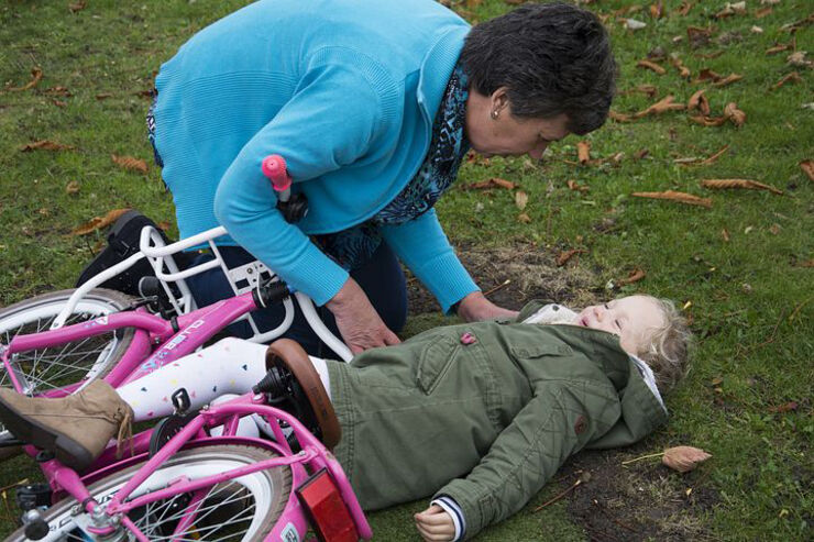 Äldre dam hjälper flicka som trillat av cykel