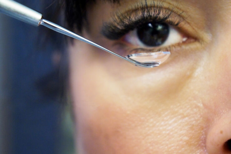Närbild på en kvinnas öga med en kontaktlins på ett instrument framför ögat.