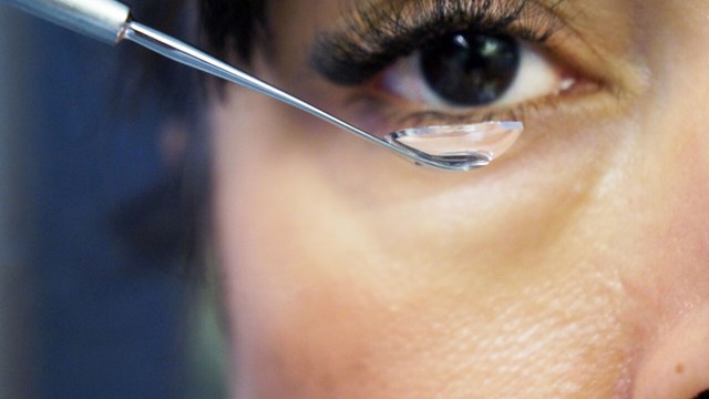 A close up on a womans eye with a contactlens in the forefront.