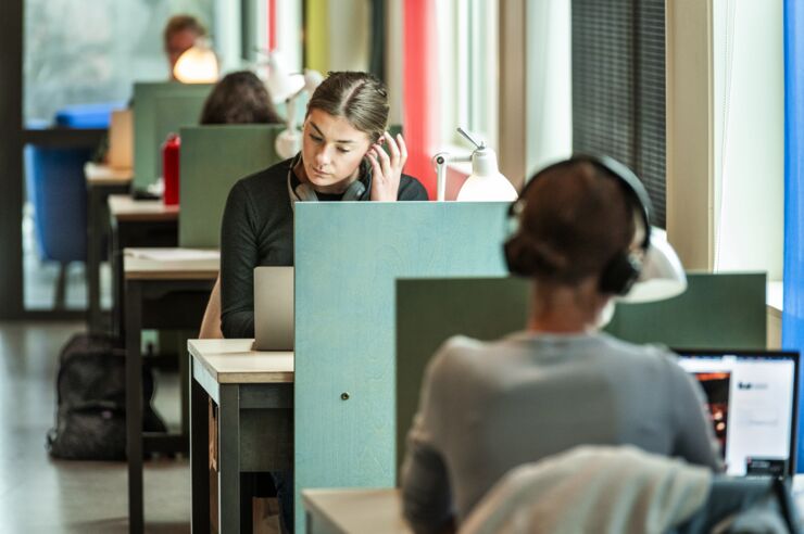 Four students sitting at a row of study seats.