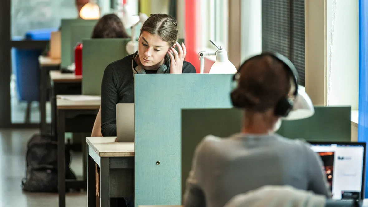 Four students sitting at a row of study seats.