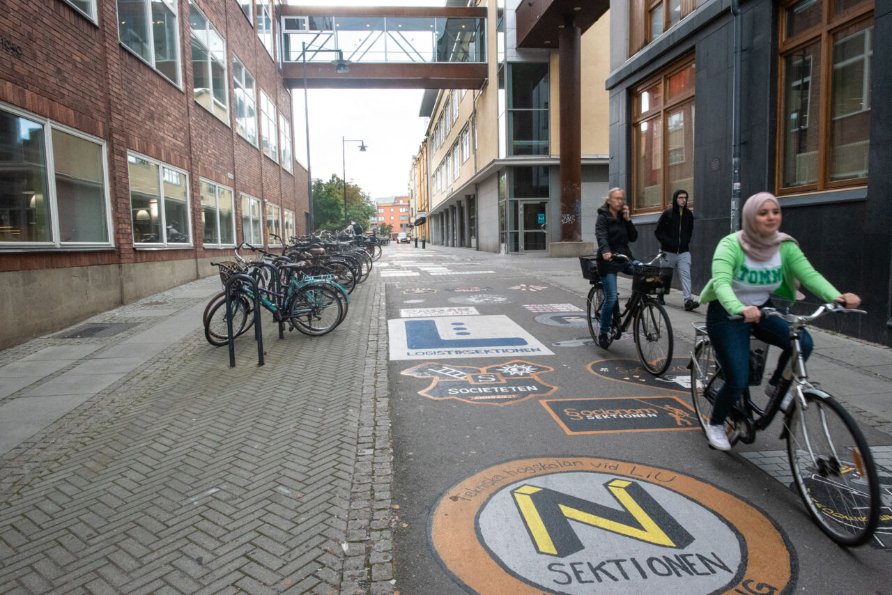 People cycling down a slope with painted emblems.