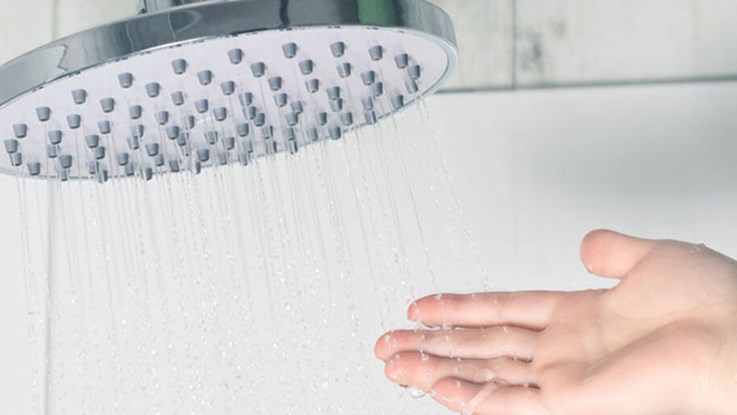 Hand vidrör vattnet från en dusch