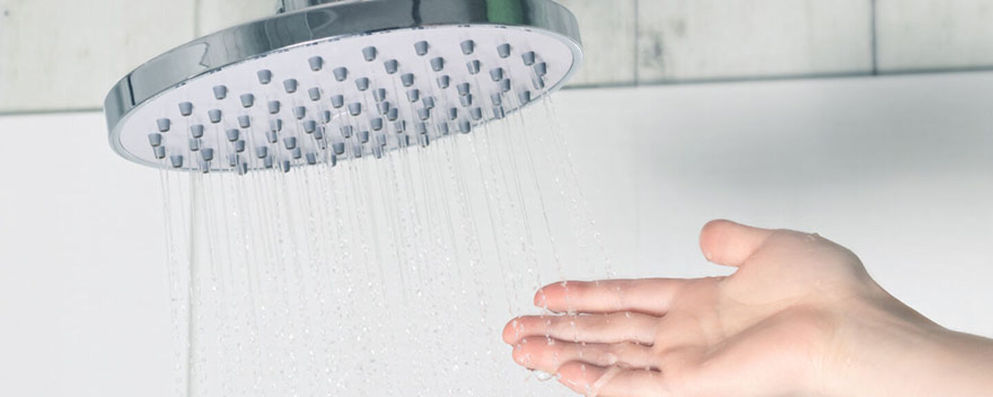 Hand vidrör vattnet från en dusch