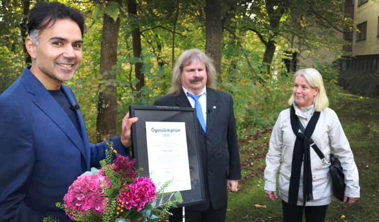 Forskaren Neil Lagali till vänster ler och håller blommor och pristavlan från Synskadades riksförbund. I mitten står förbundsordföranden Håkan Thomsson och till höger står distriktsledamoten Malin Löfvenberg, de delade ut priset.