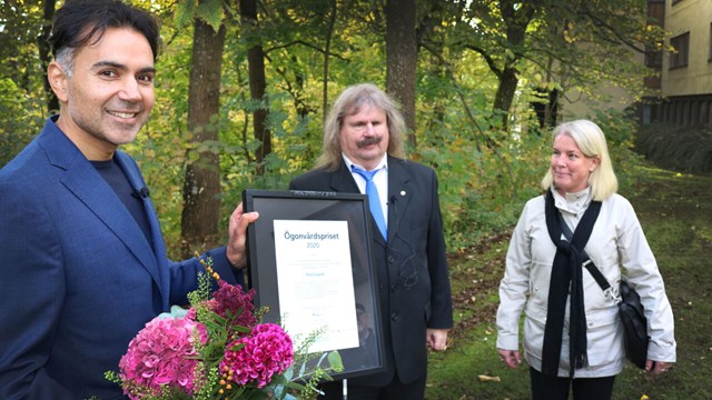 Forskaren Neil Lagali till vänster ler och håller blommor och pristavlan från Synskadades riksförbund. I mitten står förbundsordföranden Håkan Thomsson och till höger står distriktsledamoten Malin Löfvenberg, de delade ut priset.