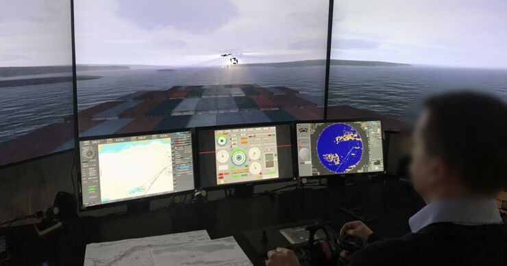 A person sits infront of simulation of the bridge of a cargo ship