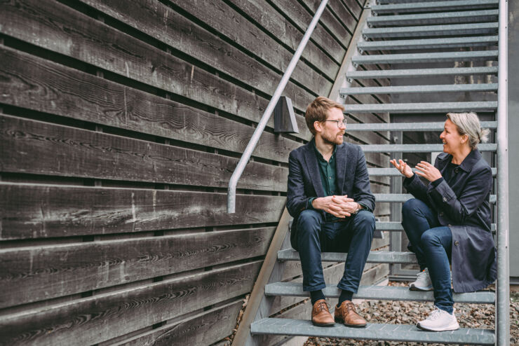 Two people are sitting on a staircase outside and talking.