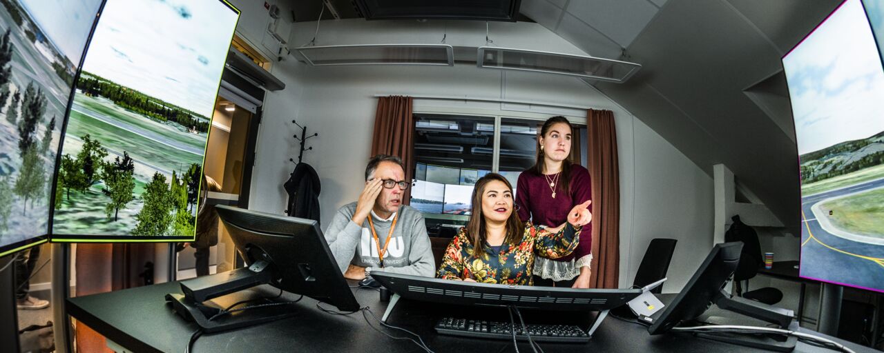 Three people watching screens showing a simulation