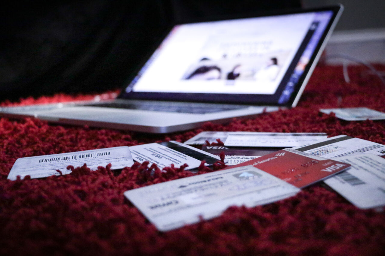 En uppslagen dator och kreditkort utspridda på en röd matta. 