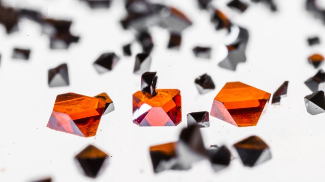 Perovskiter, som liknar svarta och röda kristaller, ligger på ett ljusbord.