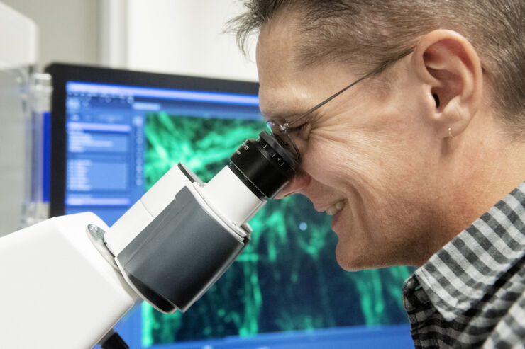 Vesa Loitto using a microscope.