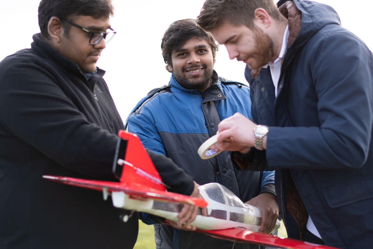 Tre studenter justera sin flygplans konstruktion