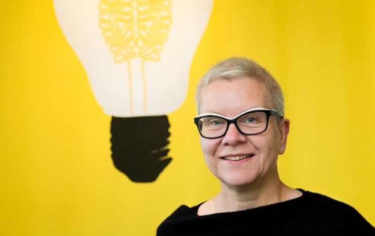 Eva Hemmungs Wirtén framför en gul vägg med en glödlampa. Hon leder forskningsprojektet Passim.