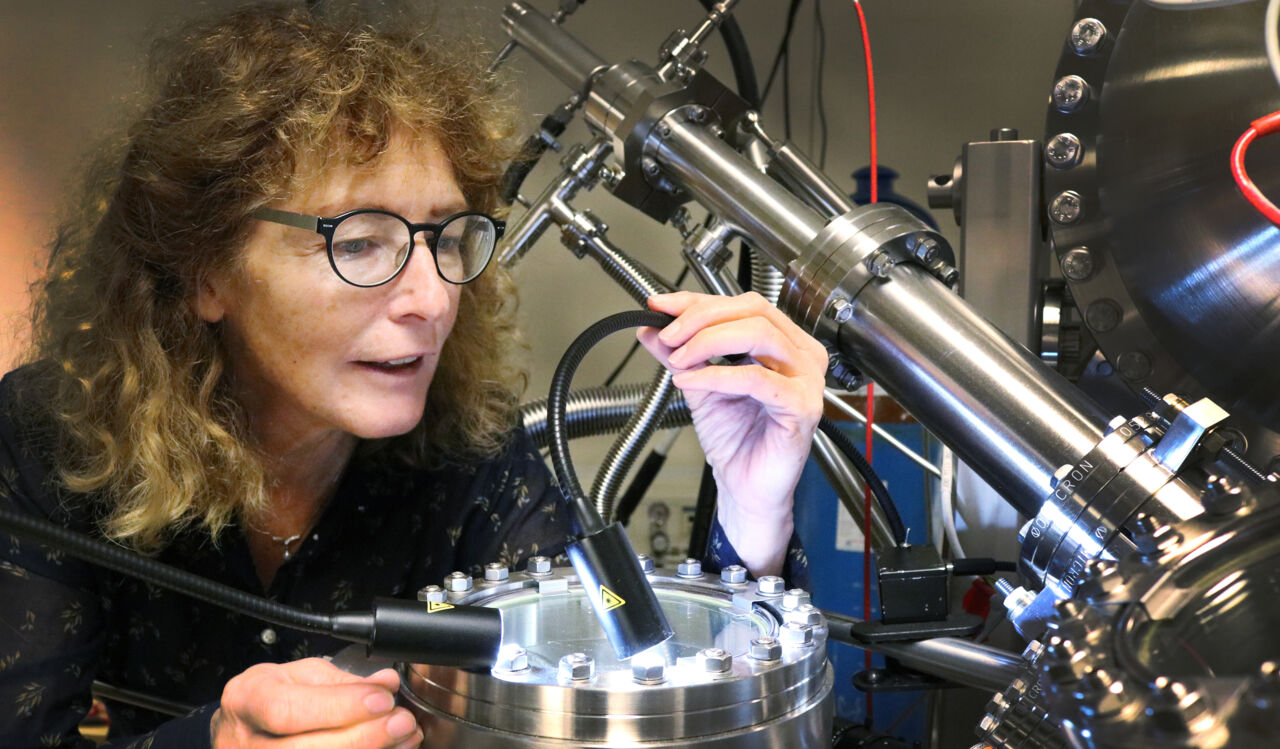 Kvinnlig forskare vid stor maskin på fysiklabbet.
