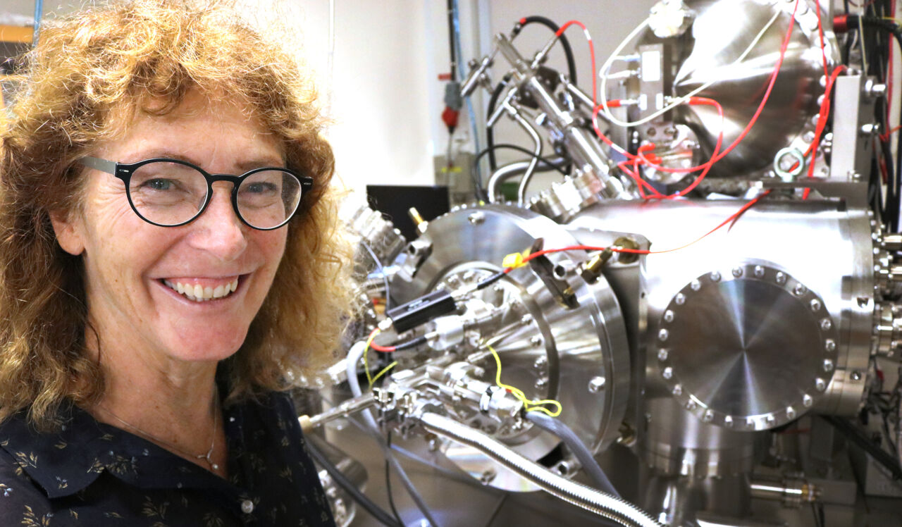 Kvinnlig forskare vid stor maskin på fysiklabbet.