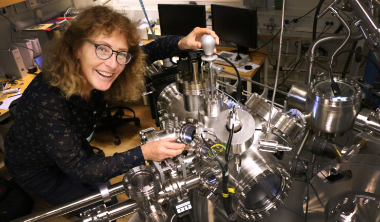 Woman, researcher standing by machine in the lab.