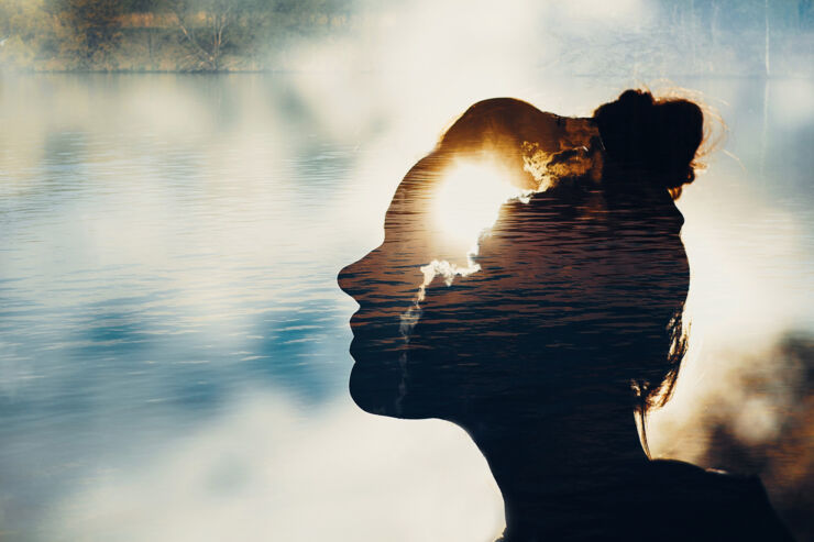 A double-exposed photo with a silhouette of a woman who seems to have the sun in her head.