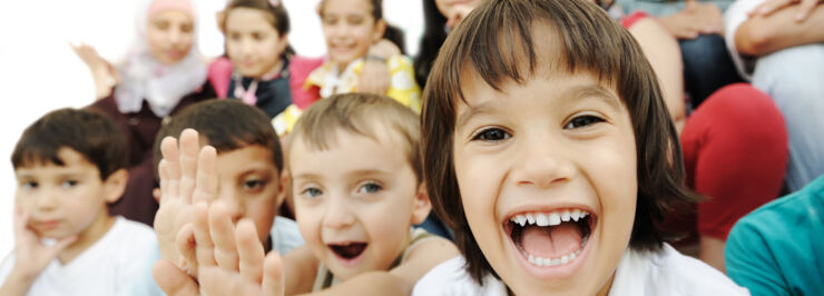  Several happy children, one of whom waves to the camera.