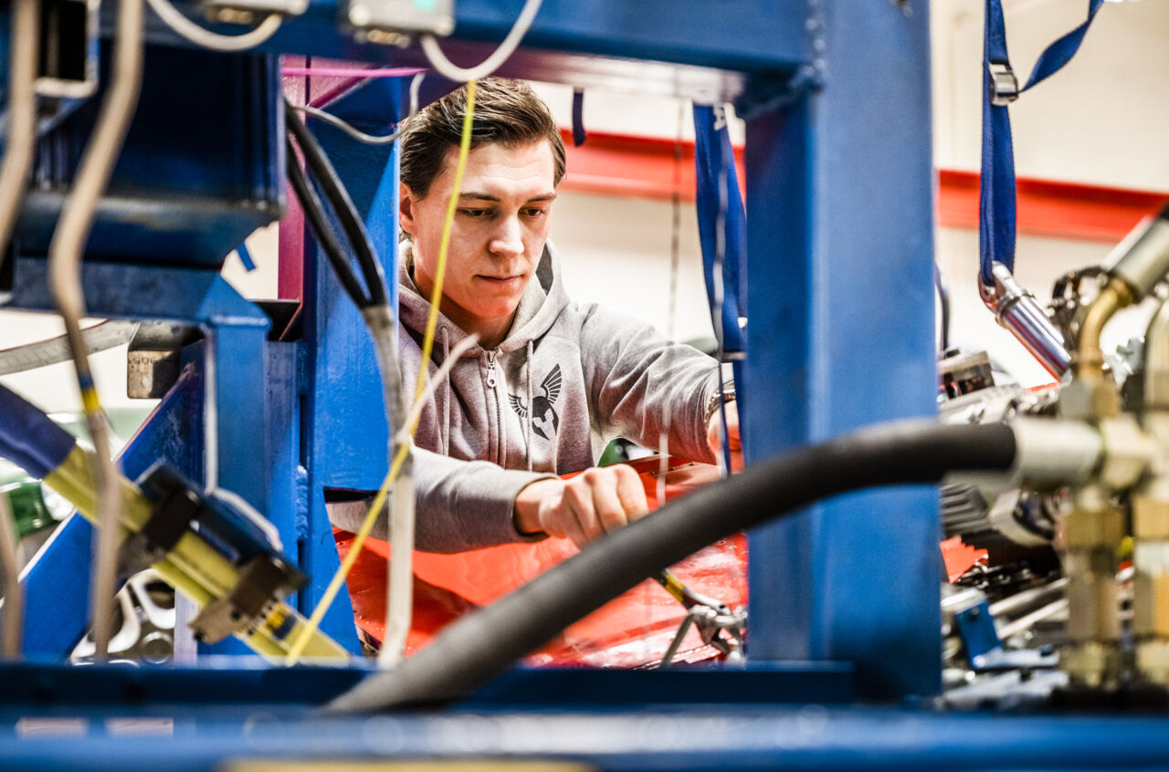En forskare står och skruvar på en flygplansvinge.