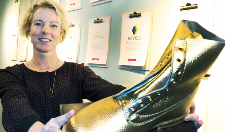 Woman by a wall full of golden-coloured shoes. 