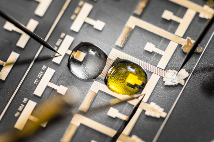 Two droplets, one yellow and one clear, on circuits.