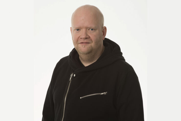 Portrait of Johan Israelsson. He has a black hoodie on and the background is white.