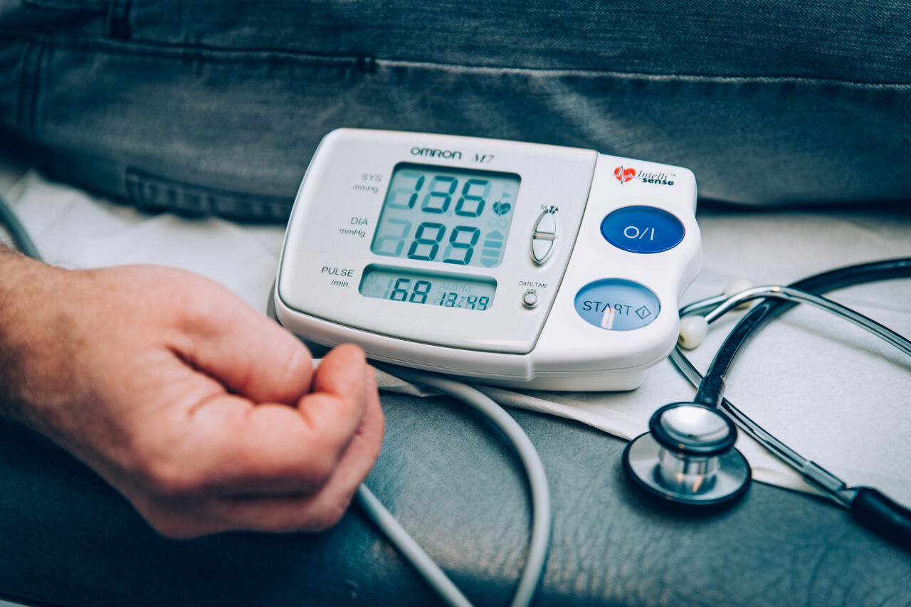 Närbild på en hand bredvid en dosa som mäter pulsen.