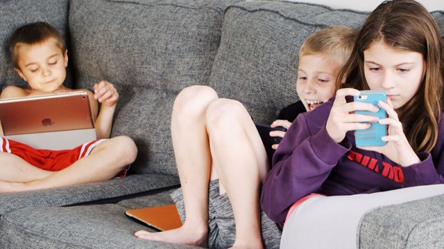 Barn tittar på sina datorer och telefoner.
