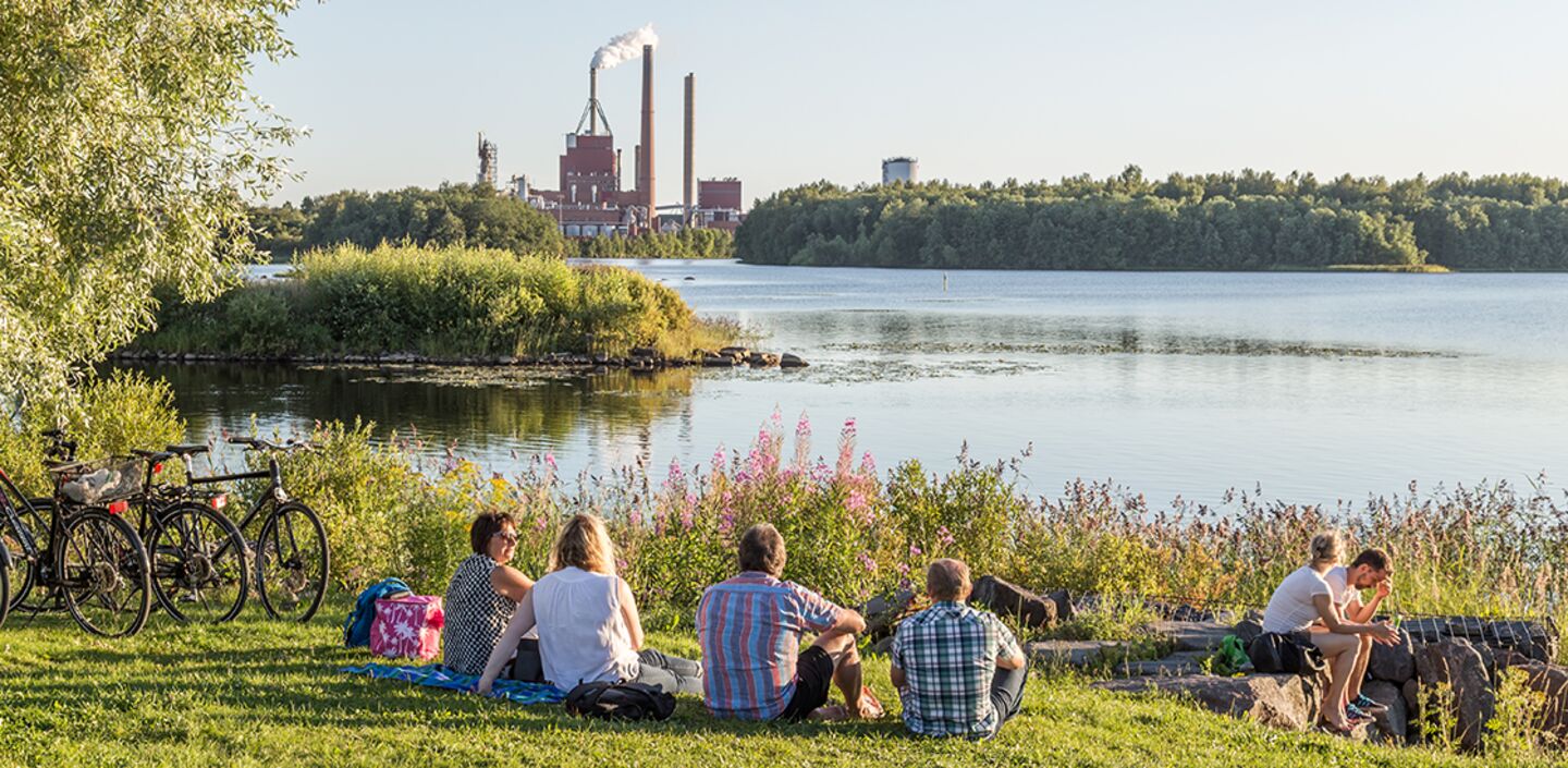 People sitting near industrial plant in Oulu, Finland.