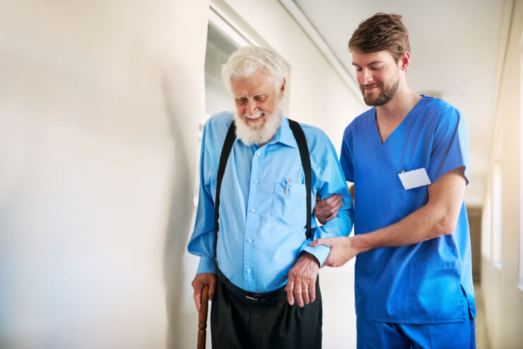 Male nurse helping older man to walk