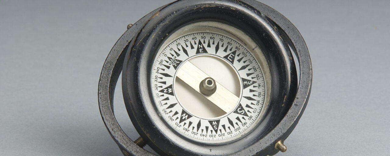 Older compass against a grey background.