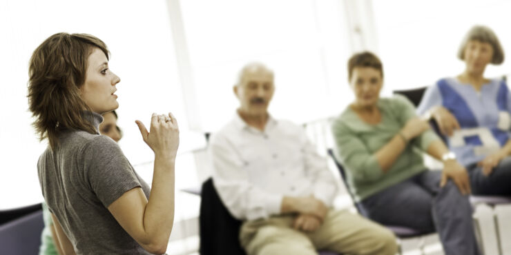 Female teatcher talking in front of a group adult students. 