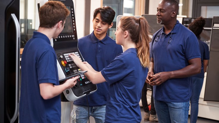 A group of students looking at a machine. 