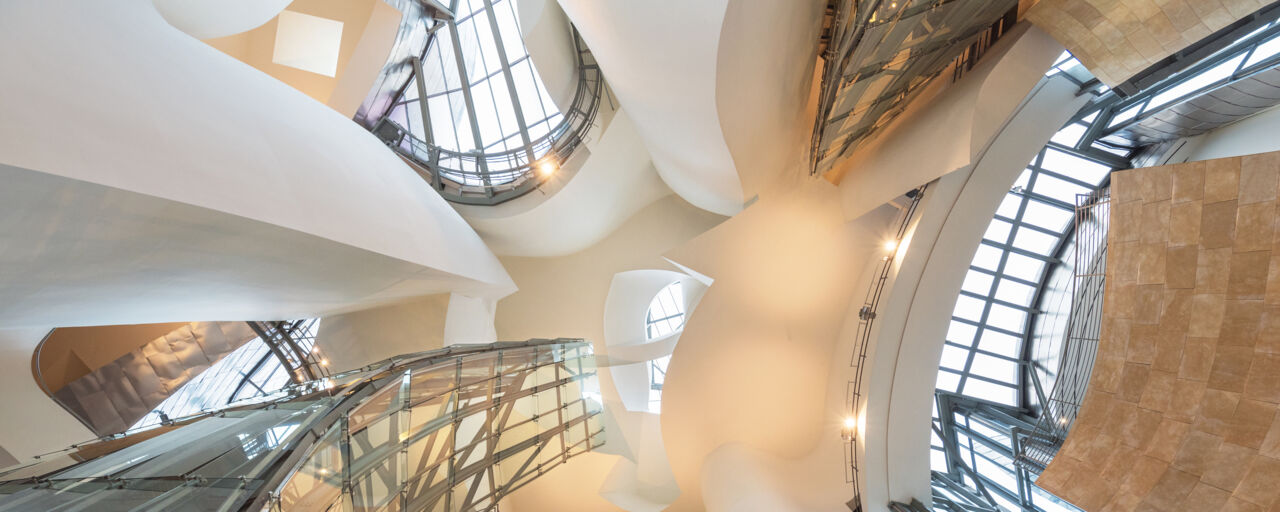 Bild inifrån Guggenheim museet i Bilbao. Taget underifrån så att ljusa trappor, fönster och ljus bildar en spännande arkitektur.