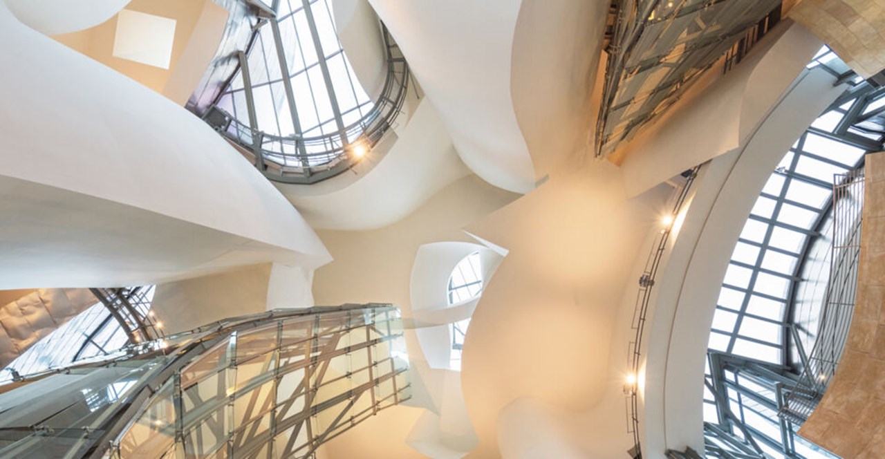 Bild inifrån Guggenheim museet i Bilbao. Taget underifrån så att ljusa trappor, fönster och ljus bildar en spännande arkitektur.