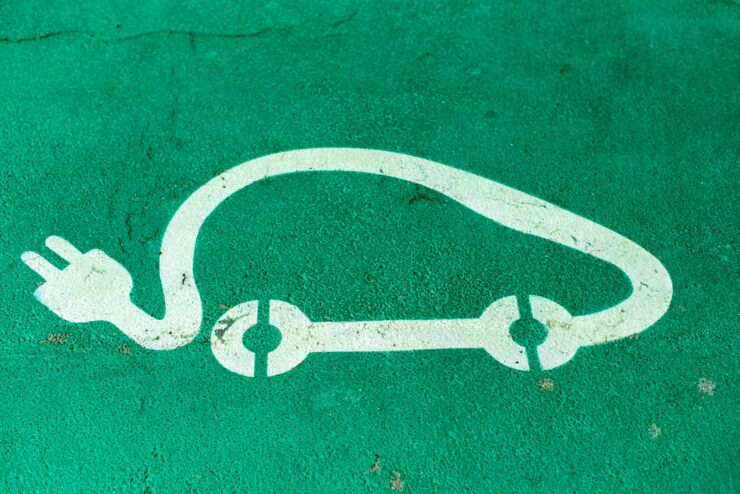 Symbol för elbil tecknad mot grön bakgrund.