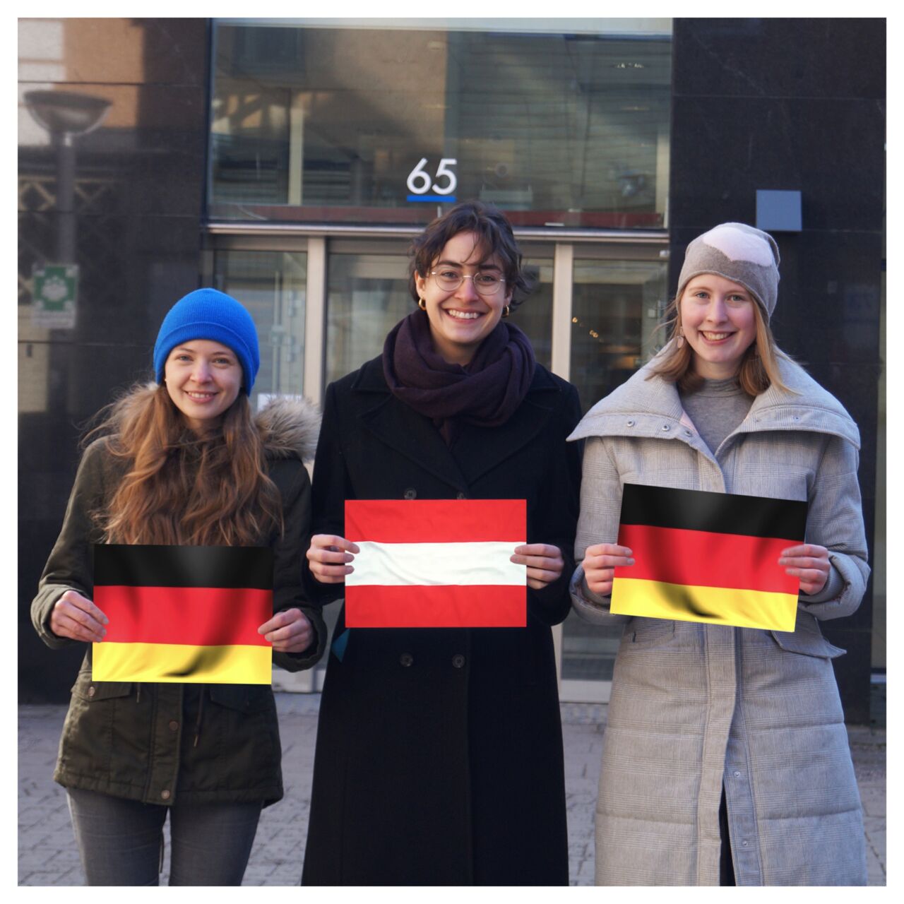 Three girls standing outside and holding up flags.