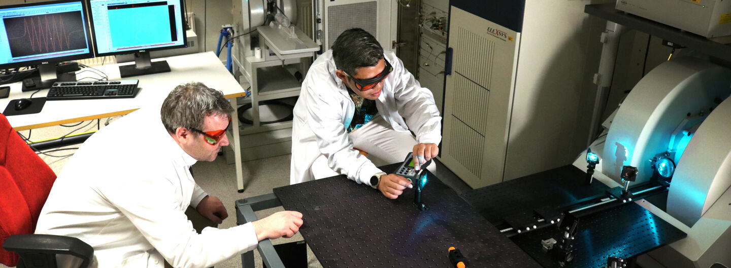 Two men by a table experimenting with light in laboratory.