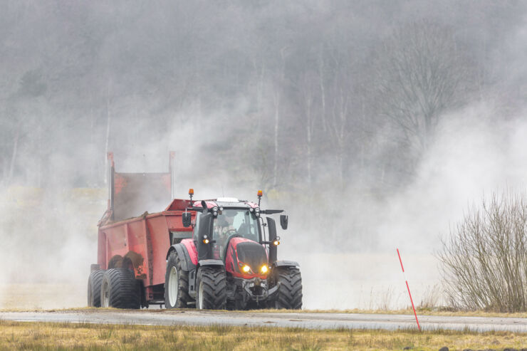 Traktor som sprider gödsel över en åker.