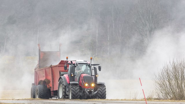 Tractor spreading fertiliser in a field.
