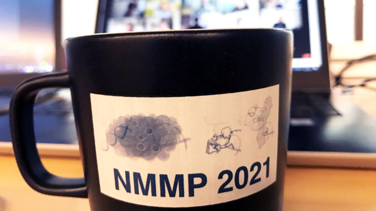 Mugg med texten NMMP 2021 framför dator med Zoommöte igång. 