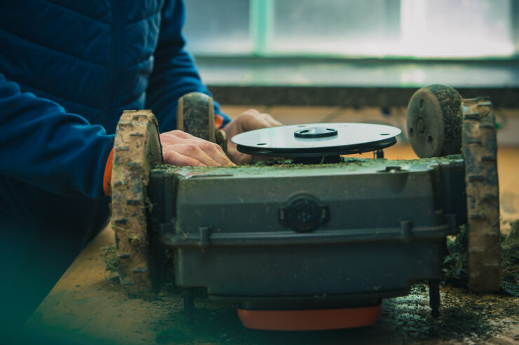 En man lagar robotgräsklippare